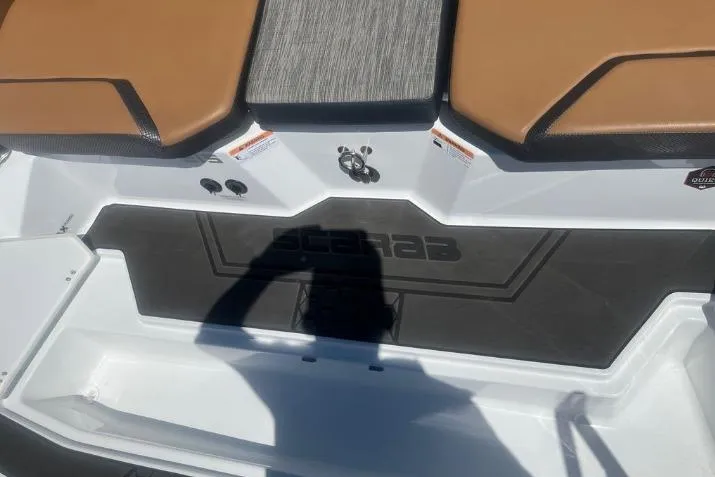 Slide: The Image of 2022 Scarab 215 SE boat interior with brown seating and black flooring. - 10