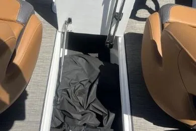 Slide: The Image of 2022 Scarab 215 SE boat interior storage compartment with black cover. - 18