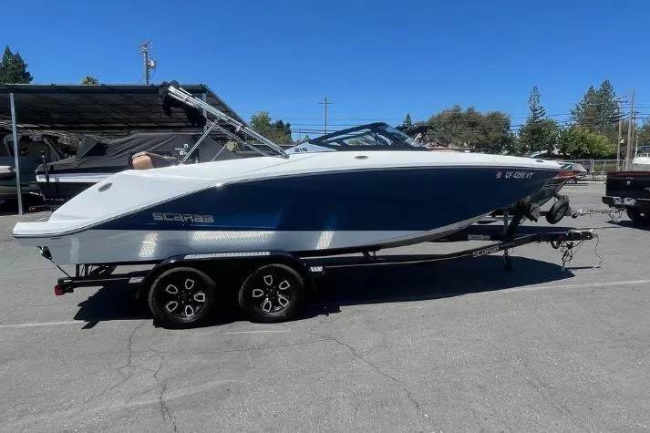 Slide: The Image of 2022 Scarab 215 SE boat on trailer, parked outdoors in a sunny setting. - 2