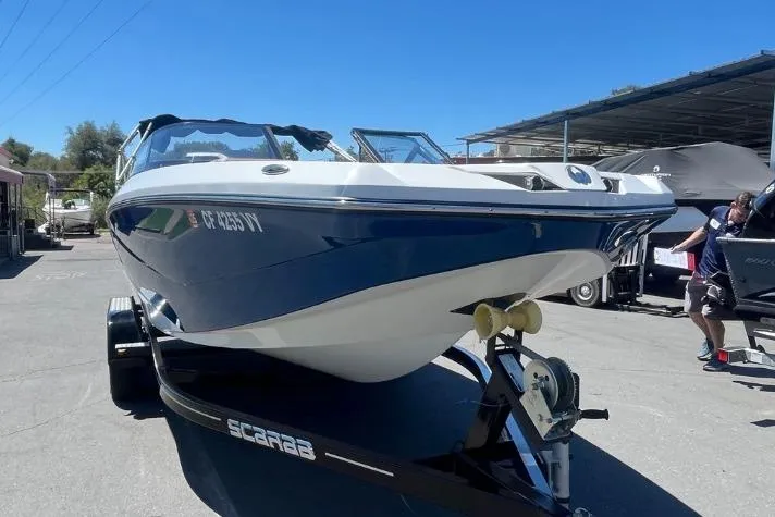 Slide: The Image of 2022 Scarab 215 SE boat on trailer, blue and white design, parked outdoors. - 28