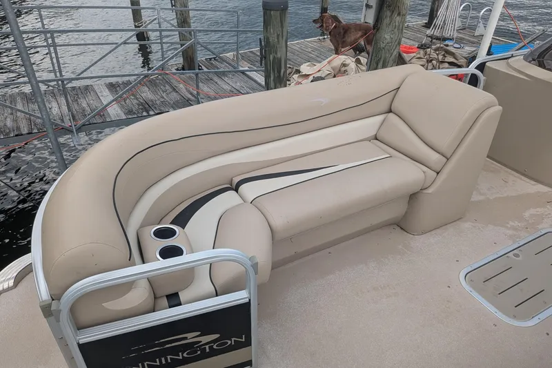 Slide: The Image of 2012 Bennington 2574 GCW pontoon boat with beige seating and cup holders at a dock. - 11