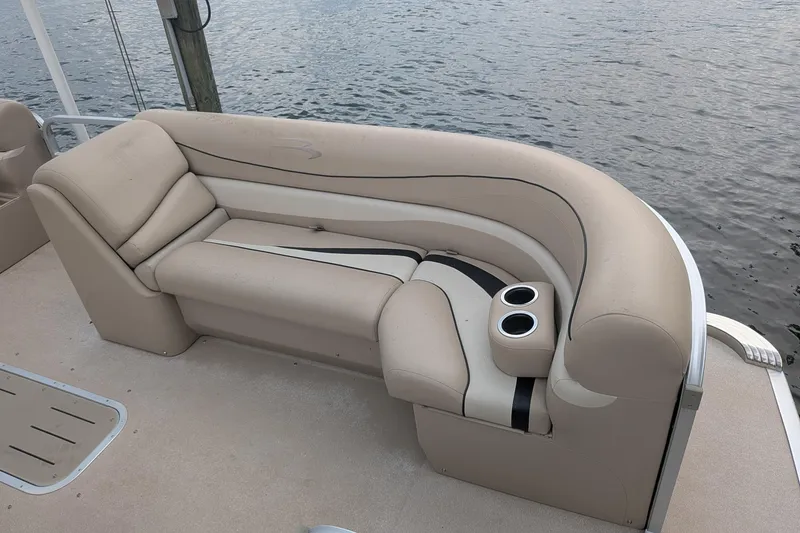 Slide: The Image of 2012 Bennington 2574 GCW boat with beige seating and cup holders by the water. - 12