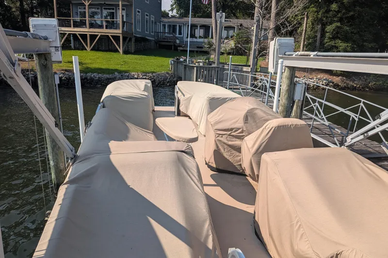 Slide: The Image of Covered 2012 Bennington 2574 GCW pontoon boat docked near a lakeside house. - 14