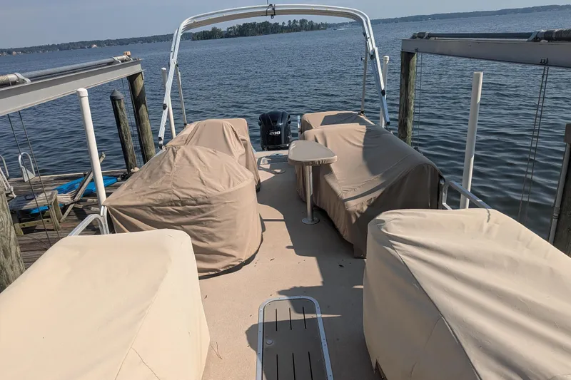 Slide: The Image of 2012 Bennington 2574 GCW pontoon boat docked, covered seats, scenic lake view. - 4