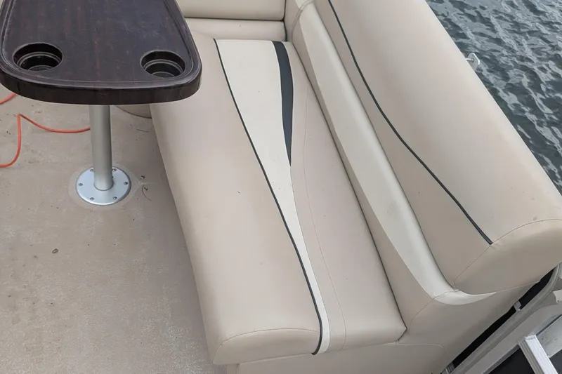Slide: The Image of 2012 Bennington 2574 GCW boat interior with beige seating and a wooden table. - 6