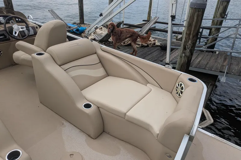 Slide: The Image of 2012 Bennington 2574 GCW boat interior with beige seating, docked by the water. - 8