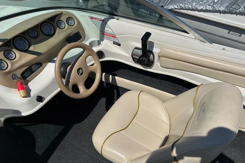Slide: The Image of 2000 Sea Ray 185 Bow Rider dashboard and steering wheel, featuring beige interior and gauges. - 7