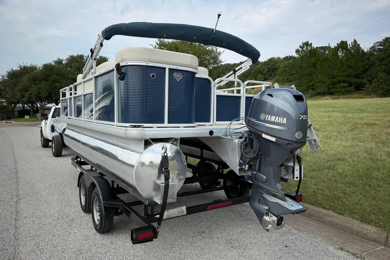 Slide: The Image of 2018 Sweetwater Sunrise 206 F pontoon boat on trailer by a lake under blue sky. - 16