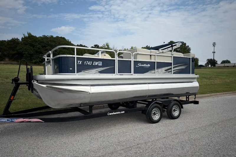 Slide: The Image of 2018 Sweetwater Sunrise 206 F pontoon boat on trailer by a lake under blue sky. - 5