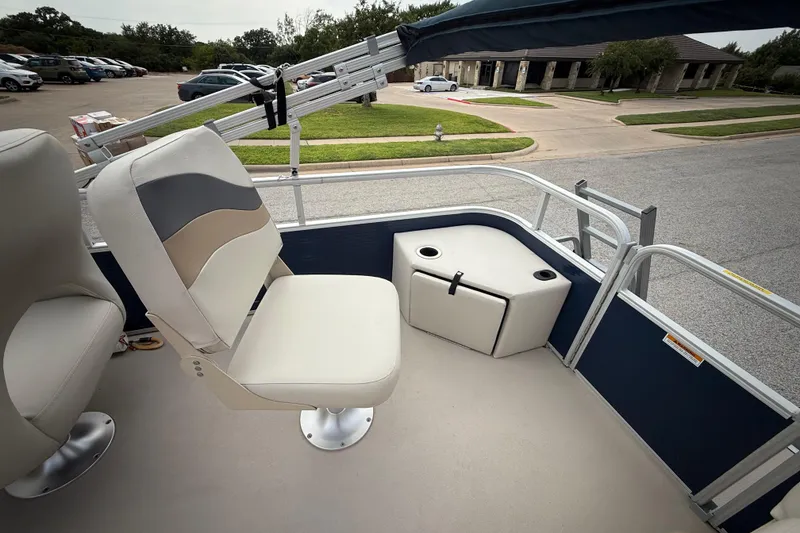 Slide: The Image of 2018 Sweetwater Sunrise 206 F pontoon boat interior with seating and railing, grassy background. - 70