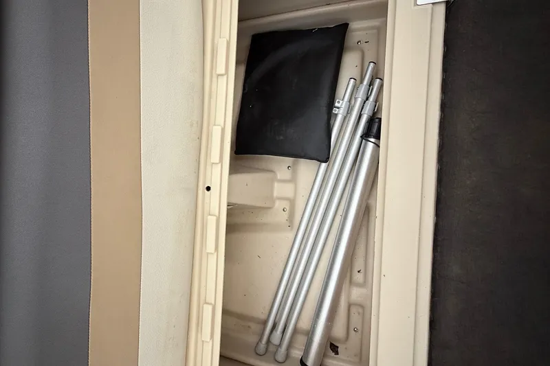 Slide: The Image of Storage compartment in a 2018 Sweetwater Sunrise 206 F boat with metal poles and a black bag. - 80
