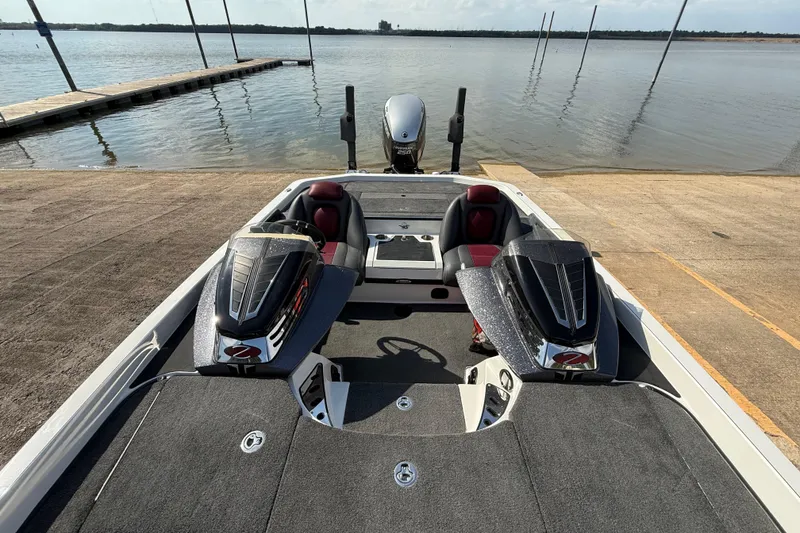 Slide: The Image of 2014 Ranger Z520 Comanche boat interior with red and black seats by a lakeside dock. - 48