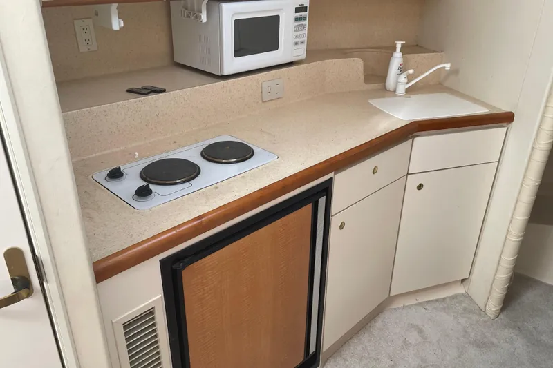 Slide: The Image of 1999 Silverton 360 Express yacht kitchenette with stove, microwave, sink, and compact fridge. - 16
