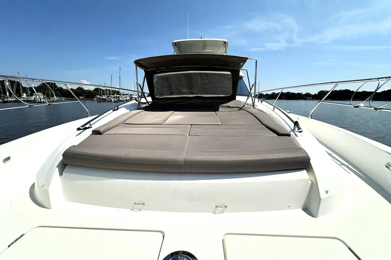 Slide: The Image of 2016 Prestige 550 yacht cruising on a calm blue sea with cityscape in the background. - 10