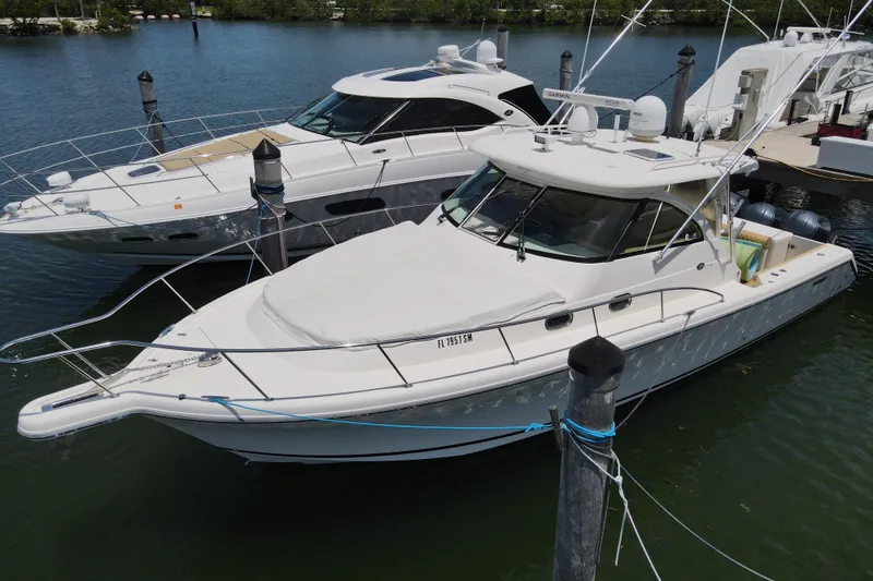 The Image of 2010 Pursuit OS 375 Offshore boat docked beside another vessel in a marina. - 0