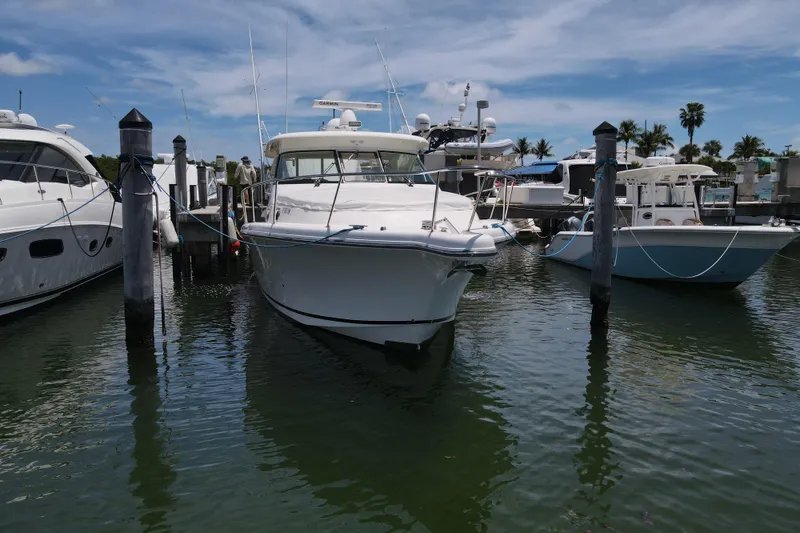 Slide: The Image of 2010 Pursuit OS 375 Offshore boat docked at marina, surrounded by other vessels. - 13