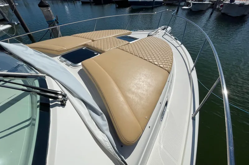 Slide: The Image of 2010 Pursuit OS 375 Offshore boat with tan cushioned sun pads on deck, docked at marina. - 18