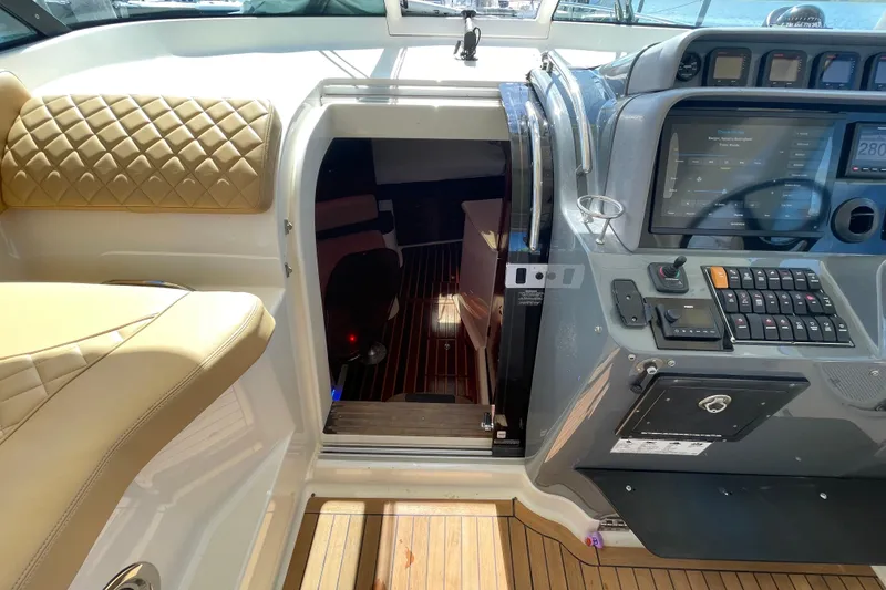 Slide: The Image of 2010 Pursuit OS 375 Offshore helm with cabin entrance, featuring modern controls and seating. - 26