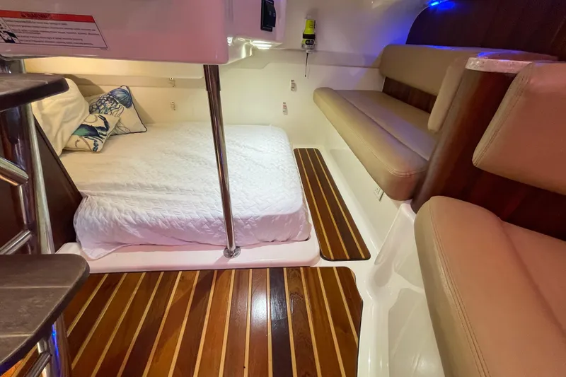Slide: The Image of 2010 Pursuit OS 375 Offshore cabin with bed, seating, and wooden flooring. - 28