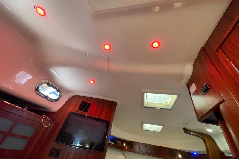 Slide: The Image of Interior of 2010 Pursuit OS 375 Offshore boat with red ceiling lights and wood paneling. - 30