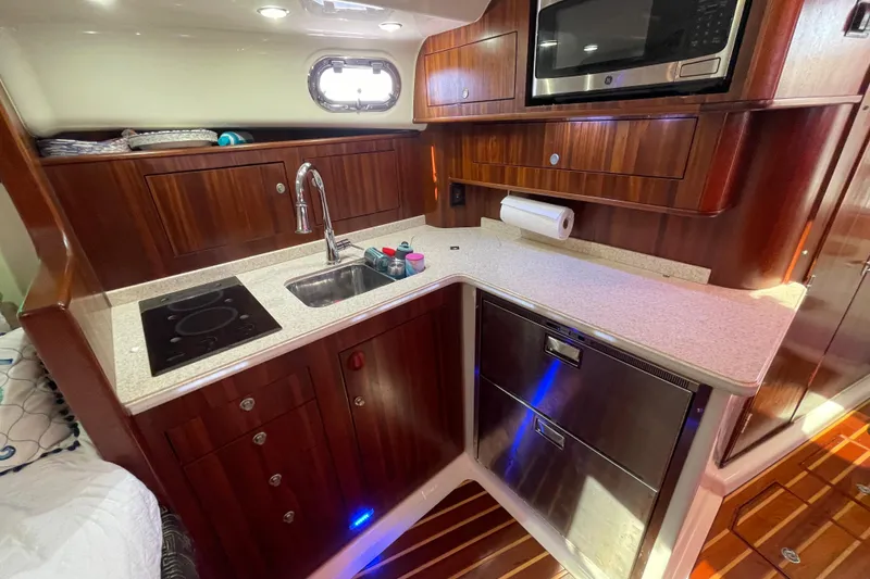 Slide: The Image of 2010 Pursuit OS 375 Offshore yacht kitchen with wood cabinetry, sink, stove, and microwave. - 31