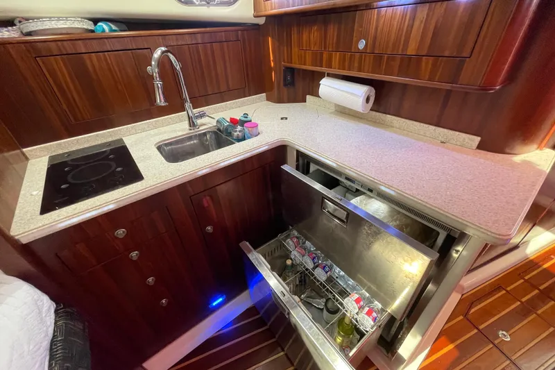 Slide: The Image of 2010 Pursuit OS 375 Offshore yacht kitchen with sink, stove, and open fridge drawer. - 32