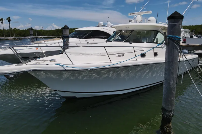 Slide: The Image of 2010 Pursuit OS 375 Offshore boat docked in a marina under a clear blue sky. - 7