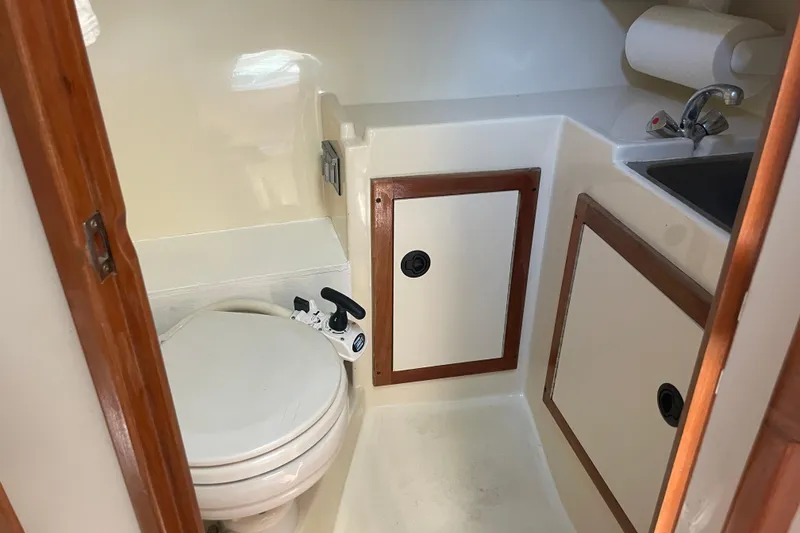 Slide: The Image of 1999 Albin 28 Tournament Express boat bathroom with toilet, sink, and storage cabinets. - 5