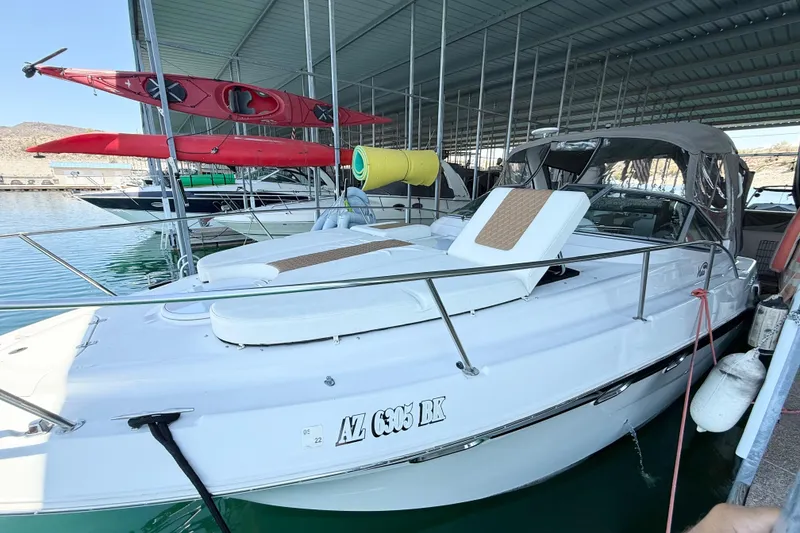 Slide: The Image of 2004 Four Winns 298 Vista boat docked, with kayaks overhead in a covered marina. - 12