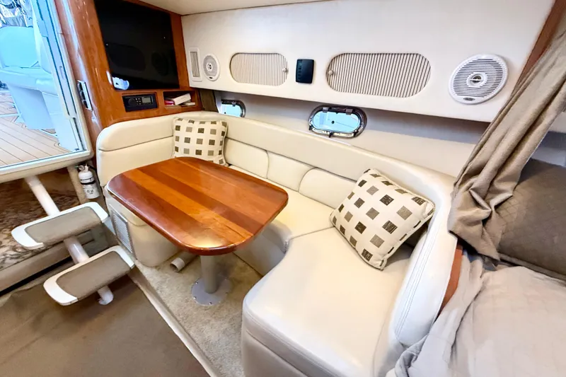 Slide: The Image of 2004 Four Winns 298 Vista cabin interior with wooden table and cushioned seating. - 27