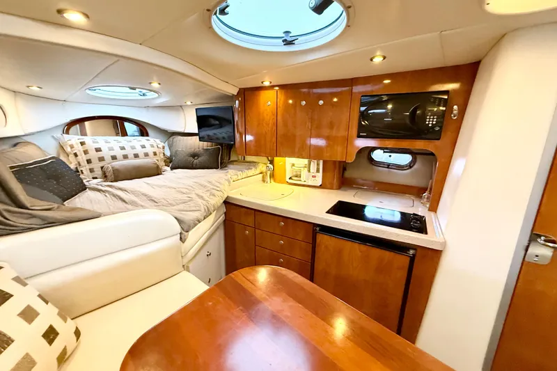 Slide: The Image of 2004 Four Winns 298 Vista cabin interior with bed, kitchenette, and wooden cabinetry. - 33