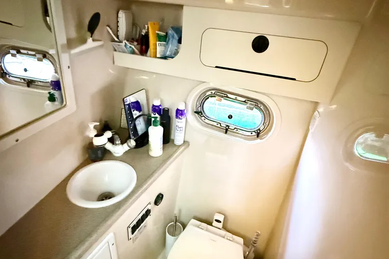Slide: The Image of 2004 Four Winns 298 Vista bathroom with sink, toiletries, and porthole window. - 34