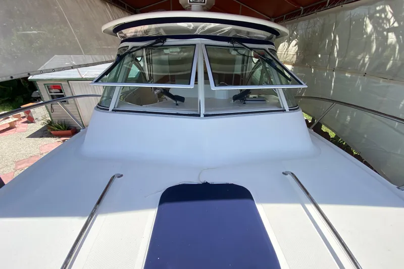 Slide: The Image of 2006 Pursuit 3480 Drummond Island Runner boat under canopy, showcasing front deck and windows. - 16