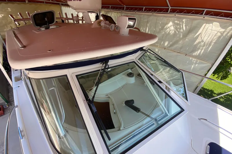 Slide: The Image of 2006 Pursuit 3480 Drummond Island Runner boat under canopy, showcasing windshield and roof details. - 17