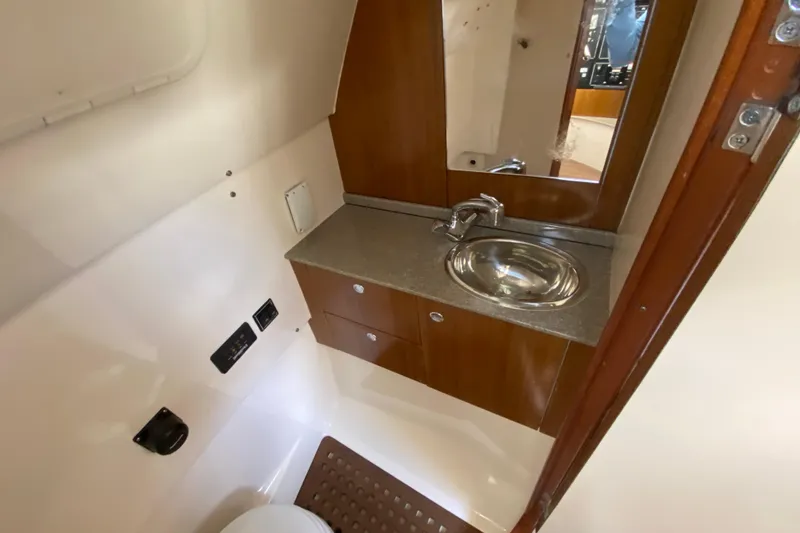 Slide: The Image of 2006 Pursuit 3480 Drummond Island Runner bathroom with sink, mirror, and wooden cabinetry. - 36