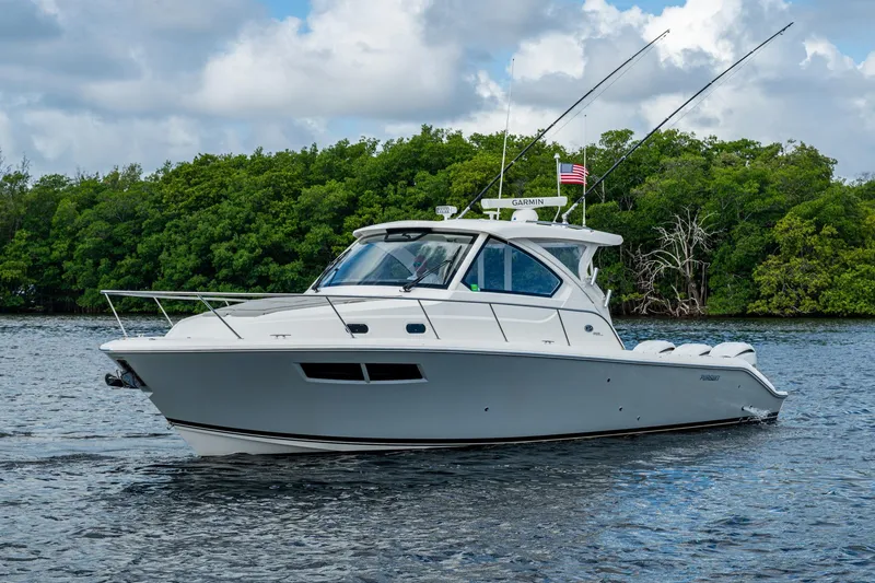 Slide: The Image of 2022 Pursuit OS 355 Offshore boat on water, surrounded by lush greenery. - 1