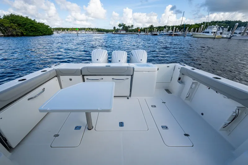 Slide: The Image of 2022 Pursuit OS 355 Offshore boat deck with seating, table, and scenic marina view. - 17