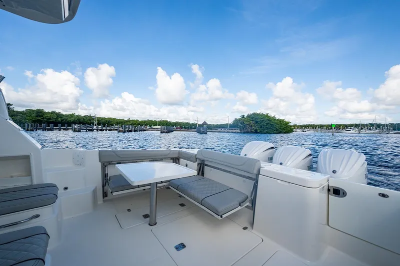 Slide: The Image of 2022 Pursuit OS 355 Offshore boat interior with seating and table, overlooking serene water and sky. - 19
