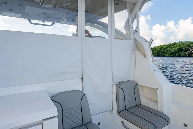 Slide: The Image of 2022 Pursuit OS 355 Offshore boat interior with seating, near water and greenery. - 23