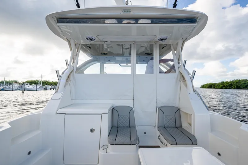 Slide: The Image of 2022 Pursuit OS 355 Offshore boat interior with seating, on a calm waterway. - 24