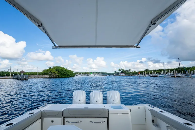 Slide: The Image of 2022 Pursuit OS 355 Offshore boat with scenic marina view under a clear sky. - 25
