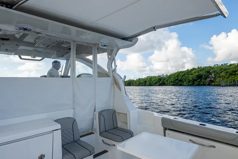 Slide: The Image of 2022 Pursuit OS 355 Offshore boat interior with seating, table, and scenic water view. - 26