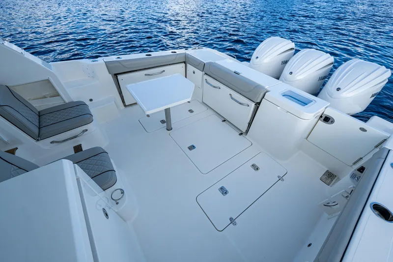 Slide: The Image of 2022 Pursuit OS 355 Offshore boat deck with seating, table, and triple outboard engines. - 28