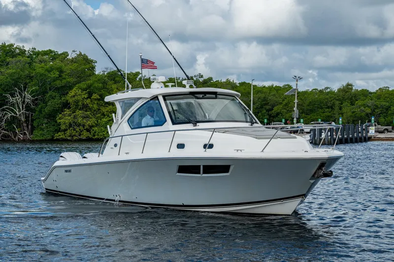 Slide: The Image of 2022 Pursuit OS 355 Offshore boat cruising on a calm waterway, surrounded by lush greenery. - 4