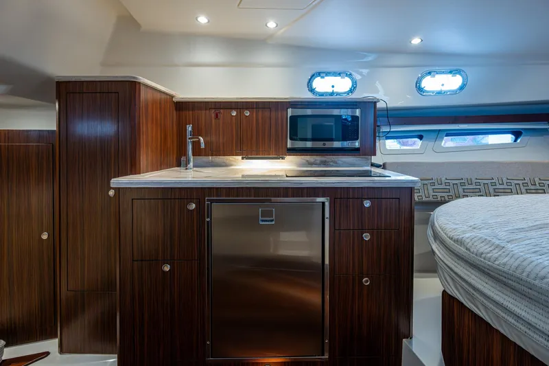 Slide: The Image of 2022 Pursuit OS 355 Offshore interior with modern kitchen, TV, and wood finish. - 46
