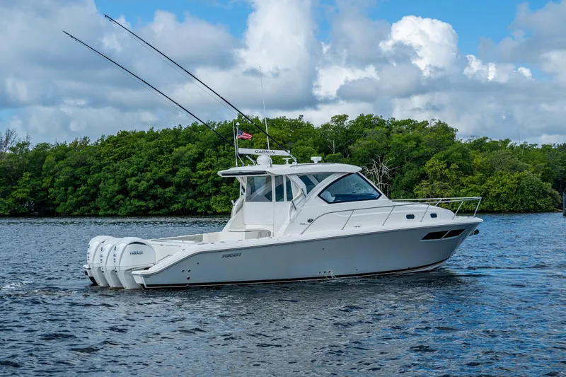 Slide: The Image of 2022 Pursuit OS 355 Offshore boat cruising on a scenic waterway with lush greenery. - 8