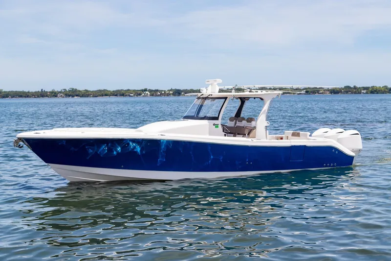 The Image of 2016 Edgewater 368CC boat on calm water, featuring a sleek blue and white design. - 0