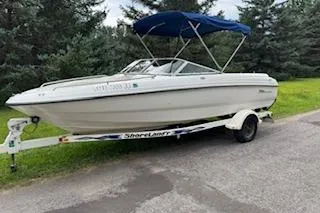 The Image of 2002 Chaparral 200 SSe boat on trailer with blue canopy, parked on roadside. - 1