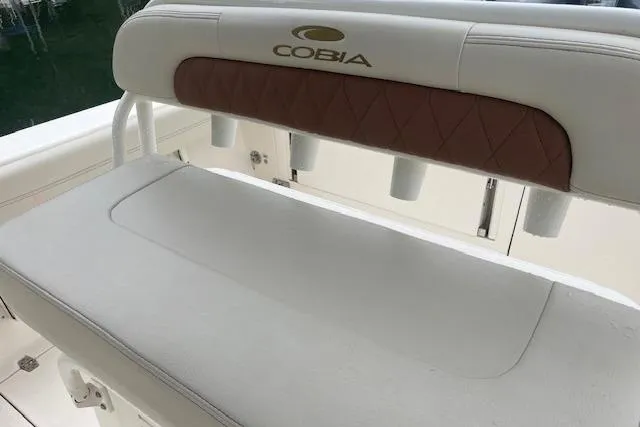 Slide: The Image of 2023 Cobia 240 Center Console boat seat with logo and rod holders. - 10