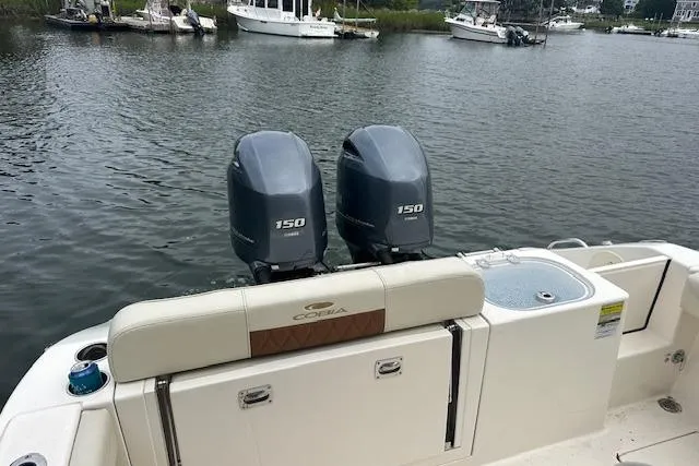 Slide: The Image of 2023 Cobia 240 Center Console boat with twin 150 engines on a calm waterway. - 20